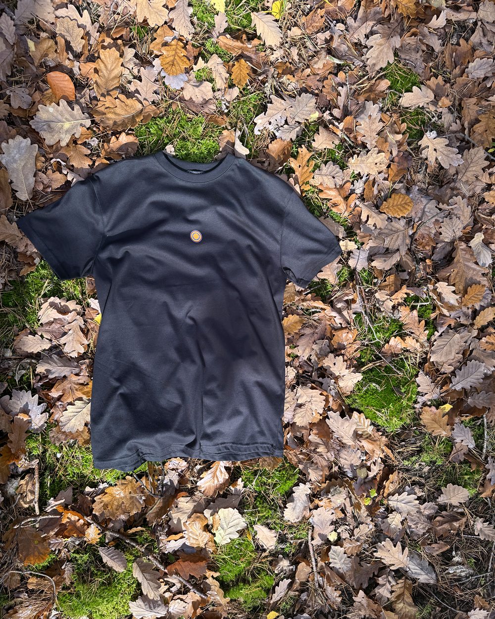 Schwarzes Nostera T-Shirt auf Laub und Moos